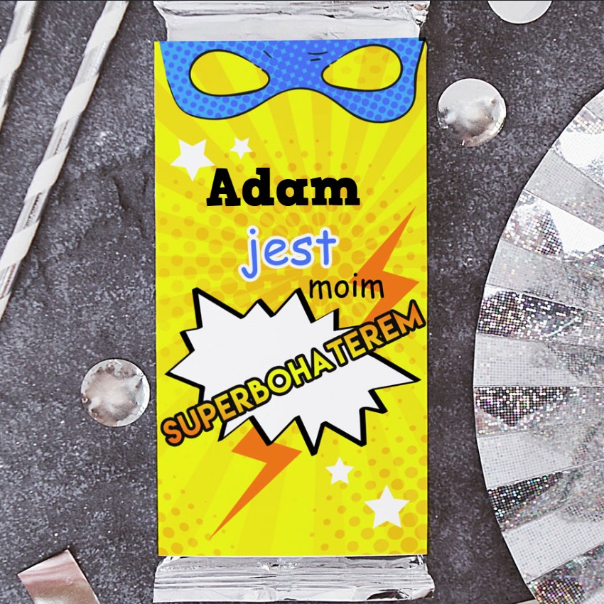 Czekolada mleczna w żółtym opakowaniu z komiksowym napisem Adam jest moim superbohaterem