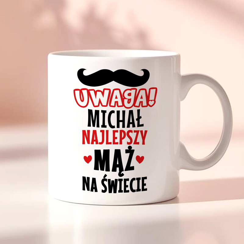 Kubek z napisem: "Uwaga! Michał najlepszy mąż na świecie" z dekoracyjnym wąsem i sercami.