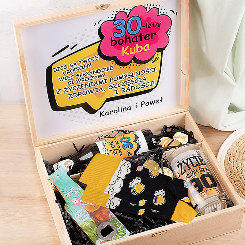 Skrzynka na urodziny z napisem "30-letni bohater Kuba", zawierająca różne prezenty i słodycze, udekorowana kolorowymi akcentami.