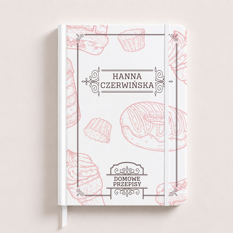 Notatnik w białej okładce z różowymi grafikami słodkości, z imieniem "Hanna Czerwińska" i napisem "Domowe Przepisy".