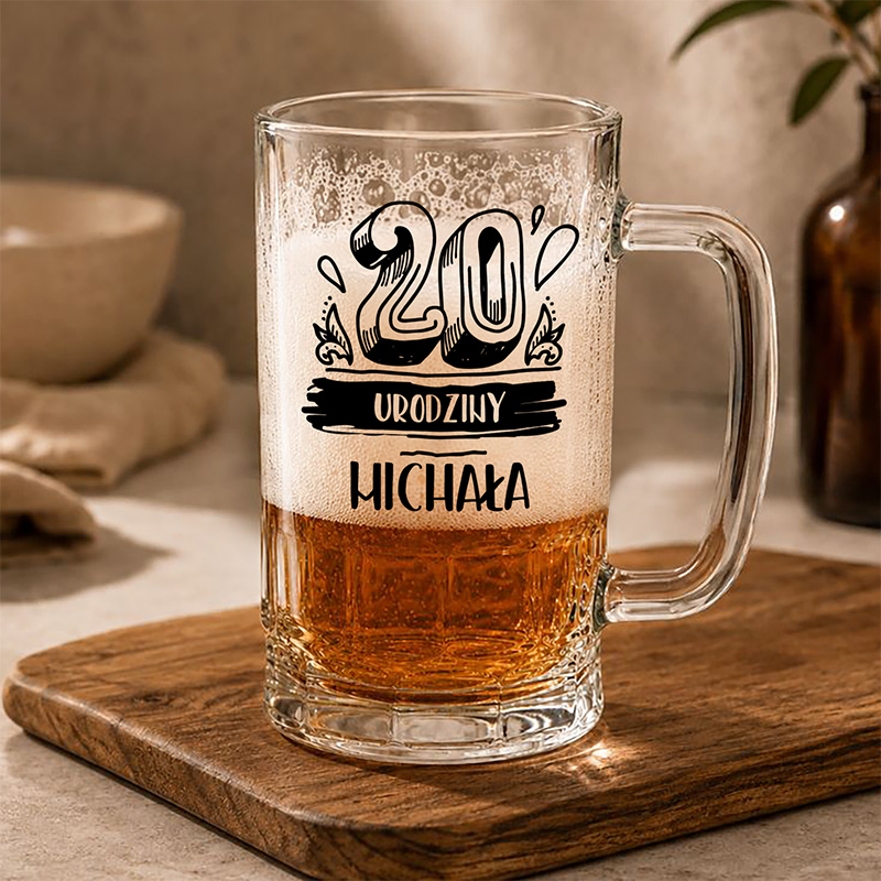 Szkło do piwa z napisem "20. Urodziny Michała", na tle drewnianego blatu i subtelnych dekoracji.