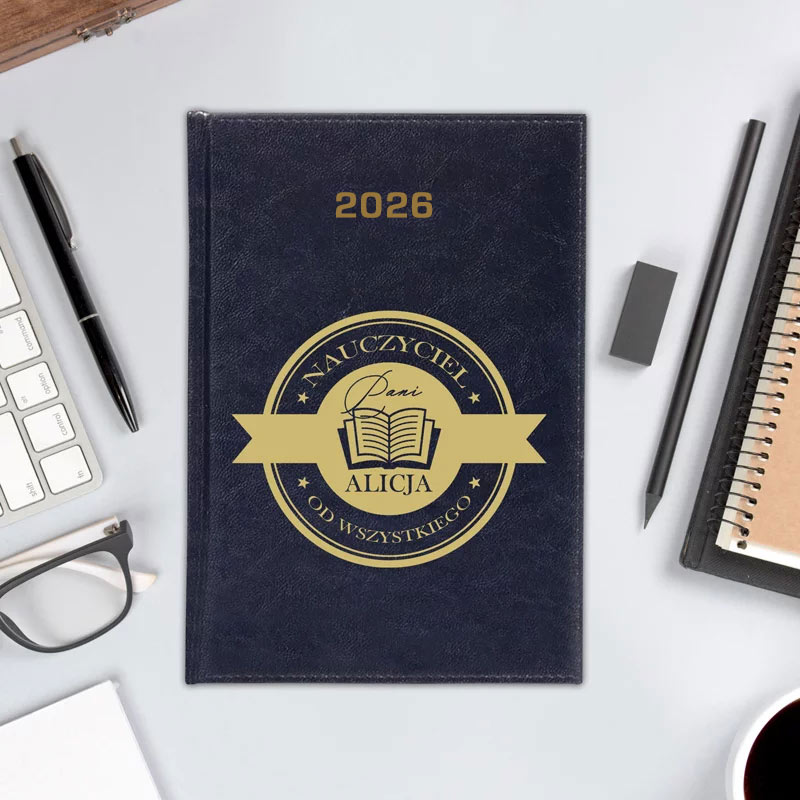 Granatowy notes z napisem '2026' i okrągłym logo 'Nauczyciel Pani Alicja Od Wszystkiego', otoczony akcesoriami biurowymi na jasnym tle.