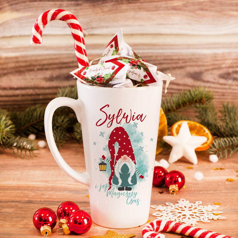 Kubek wysoki do latte wypełniony krówkami i lizakiem. Na kubku znajduje się świąteczna grafika ze skrzatem i imieniem.