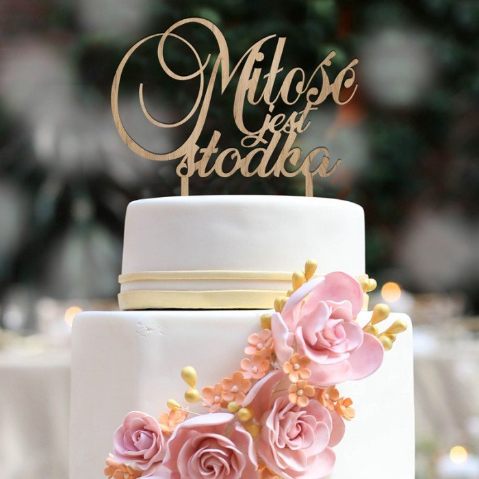 Topper ślubny na tort w postaci napisu miłość jest słodka. Wykonany jest z drewna w jasnej kolorystyce.