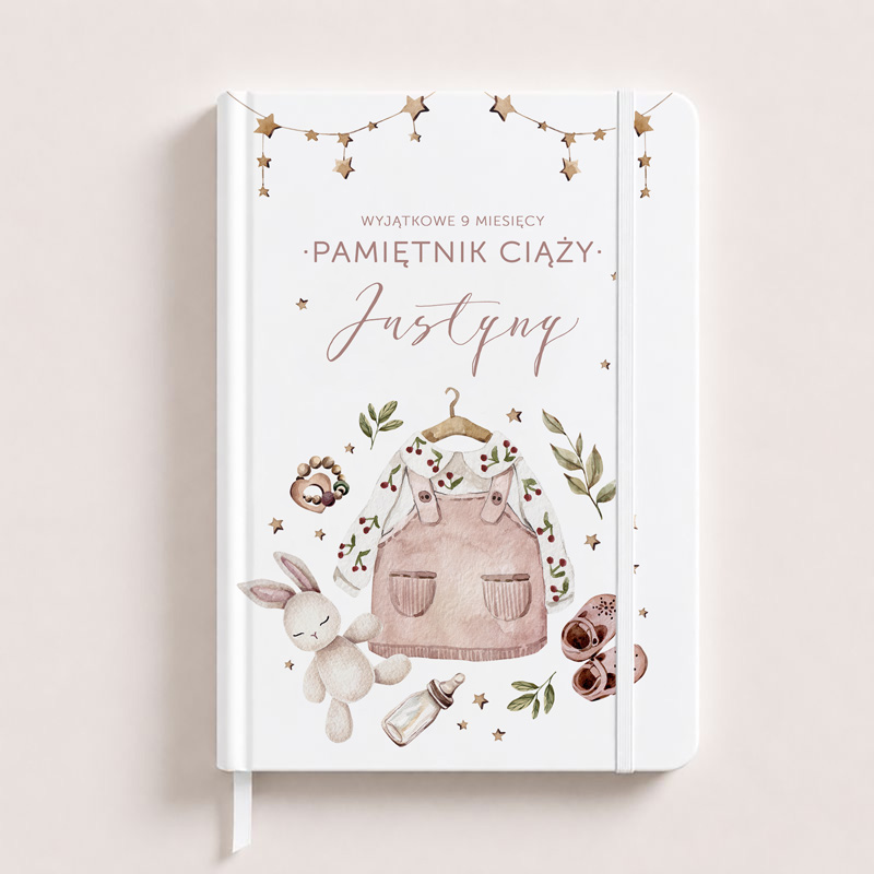 Biały pamiętnik ciąży z ilustracjami, takimi jak różowy płaszczyk, króliczek i inne akcesoria dla niemowląt.