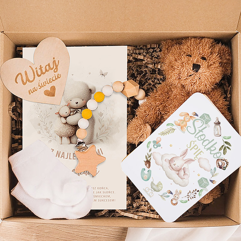Zestaw powitalny dla noworodka zawierający kartkę, przytulankę, skarpetki, gryzak i książeczkę z kolorowymi ilustracjami.