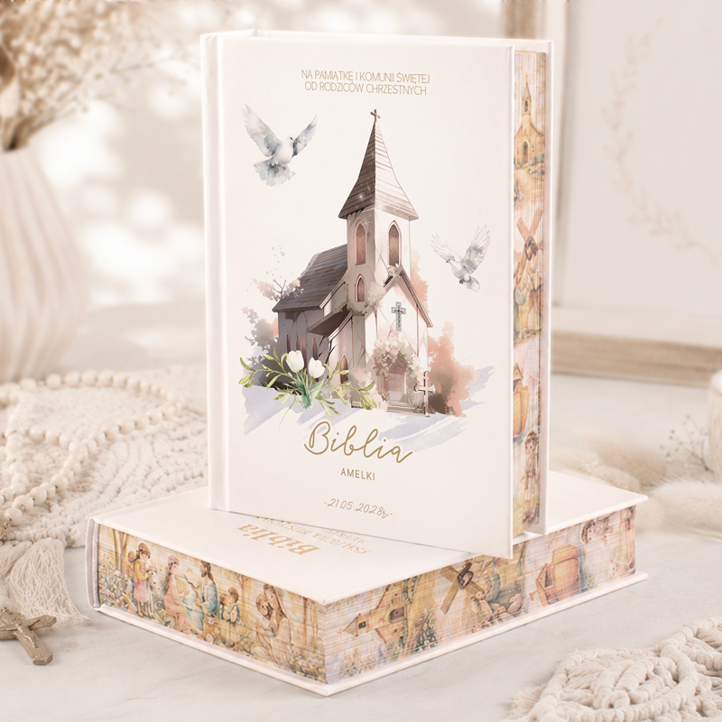 Biblia z ilustracją kościoła, białą okładką i ozdobnymi elementami, dedykowana dla Amelki z datą 21-05-2023.