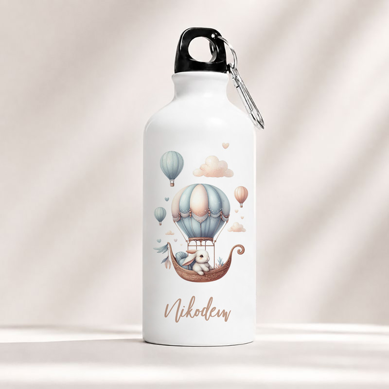 Butelka wody z ilustracją misia w balonie na gorące powietrze oraz imieniem "Nikodem" na dole.