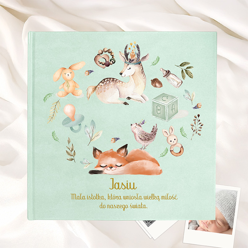 Okładka książki w kolorze miętowym, ozdobiona ilustracjami zwierząt, takich jak jelenie, lisy, zajączki i ptaki, oraz przedmiotami dziecięcymi, z napisem "Jasiu" i opisem: "Mała istotka, która uniosła wielką miłość do naszego świata."
