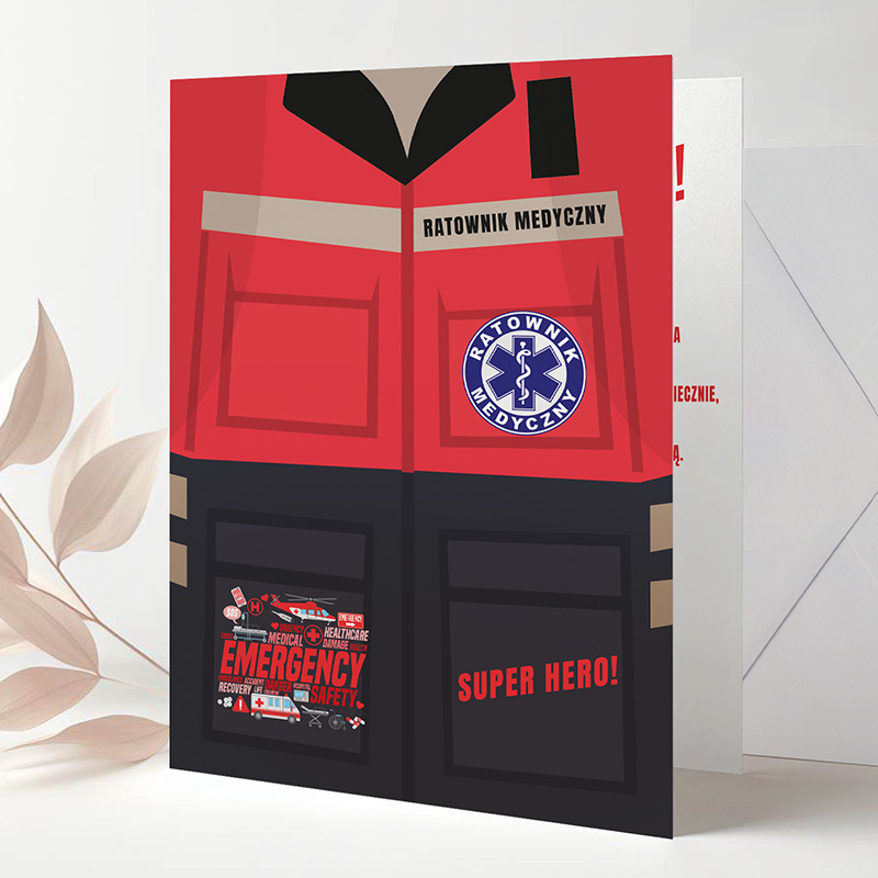 Grafika przedstawiająca czerwoną koszulę ratownika medycznego z napisem 'RATOWNIK MEDYCZNY' na górnej części oraz symbolem medycznym, obok widoczny tekst 'EMERGENCY SAFETY' i 'SUPER HERO!' na dolnej części. Tło jasne z delikatnymi roślinnymi akcentami.