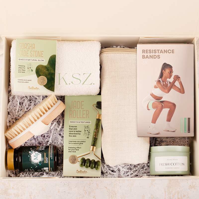 Zestaw do relaksu zawierający kamień guasha, wałek jadeitowy, ręcznik, szczotkę, opaskę do ćwiczeń oraz świecę zapachową.