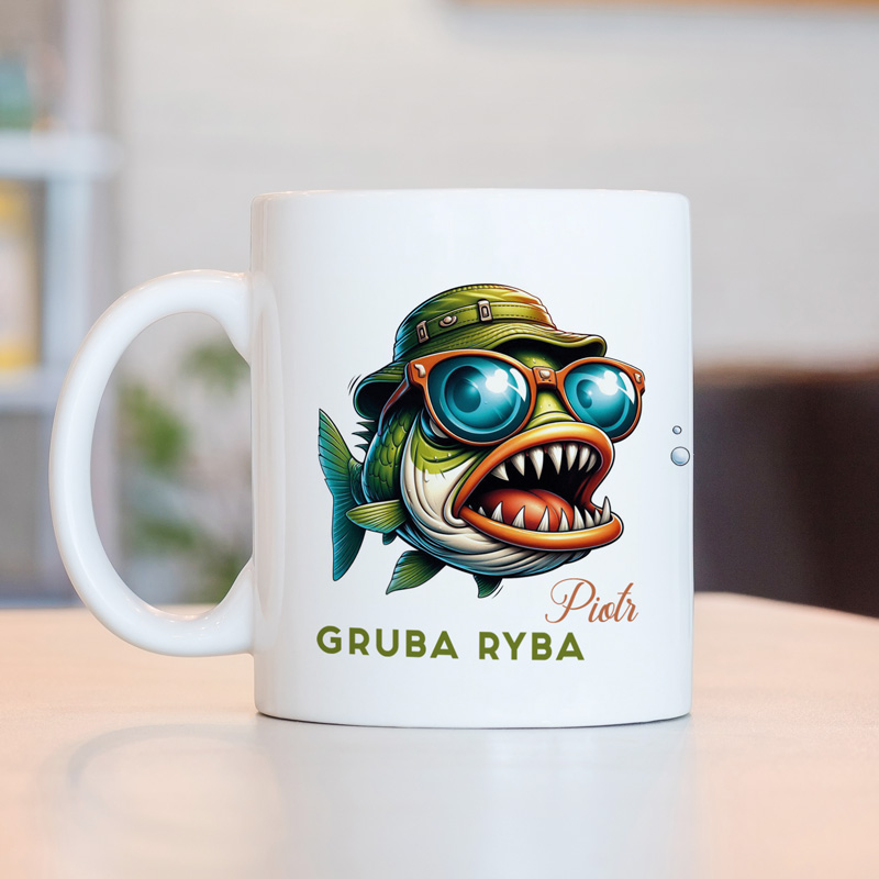 Kubek z kolorowym, graficznym rysunkiem ryby w kapeluszu i okularach, podpisany imieniem oraz tekstem 'GRUBA RYBA' w jasnej czcionce.