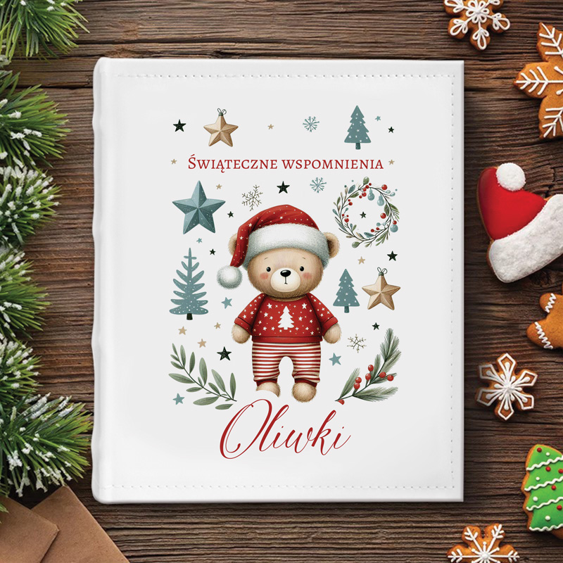 Ilustracja przedstawiająca pluszowego misia w czerwonej czapce i swetrze z choinką, otoczonego dekoracjami świątecznymi, takimi jak choinki, gwiazdy i liście, z napisem "Świąteczne wspomnienia" oraz imieniem "Oliwki".