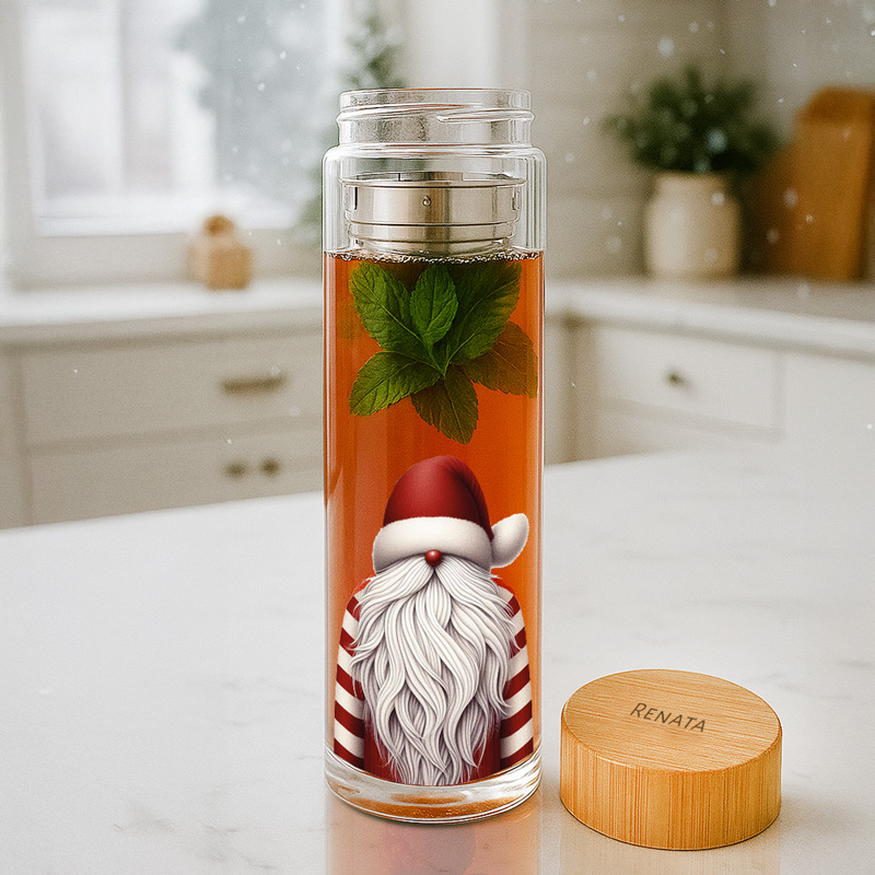 Przezroczysta szklanka z herbatą miętową, w której widoczny jest rysunek sylwetki Świętego Mikołaja w czerwono-białym stroju, na tle blatu kuchennego; obok znajduje się drewniana pokrywka z napisem 'IMIĘ'.