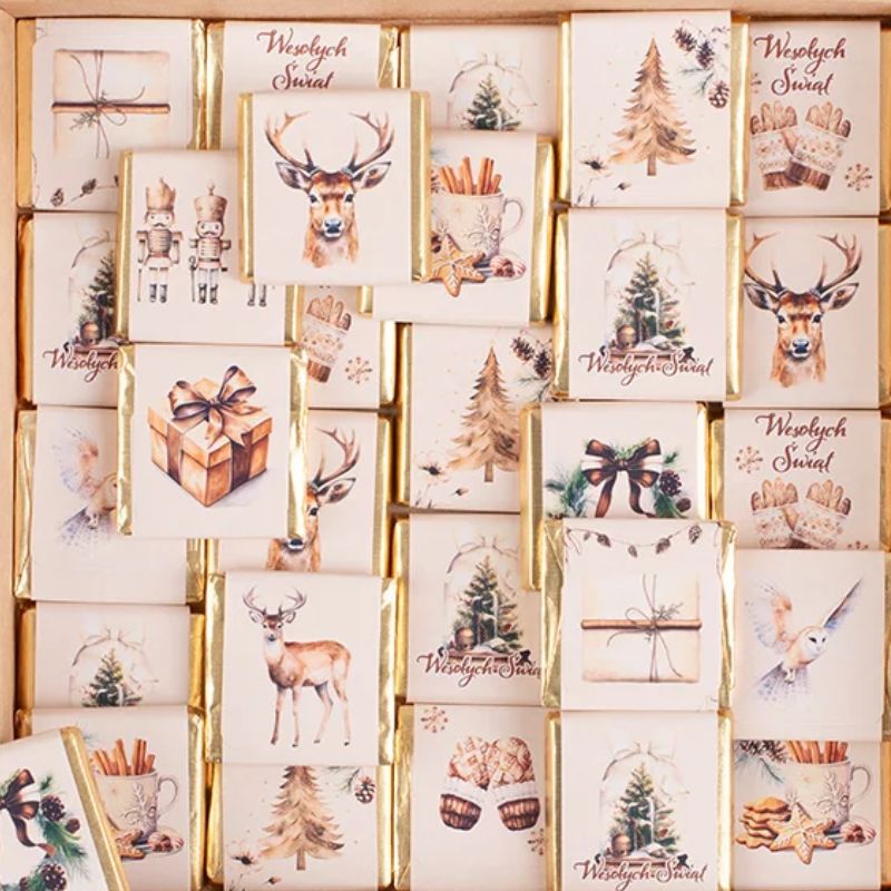 Zestaw elegancko opakowanych słodyczy świątecznych, każda paczka ozdobiona pięknymi ilustracjami, takimi jak renifery, choinki, prezenty oraz elementy bożonarodzeniowe, na tle jasnego drewna.