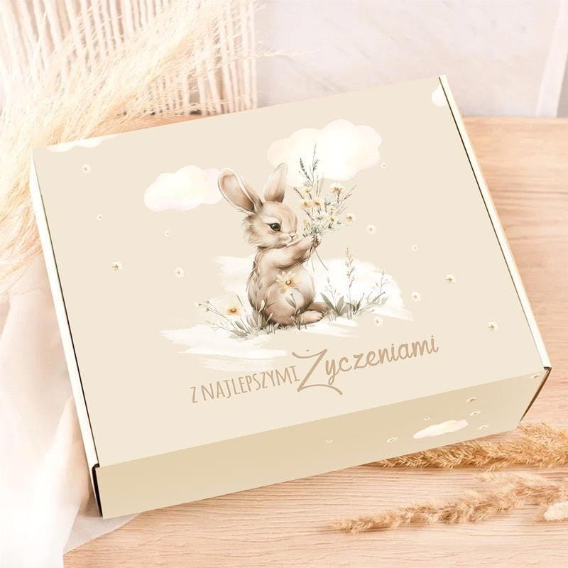 Pudełko z ilustracją króliczka trzymającego kwiaty, z napisem "Z najlepszymi życzeniami" na jasnym tle.
