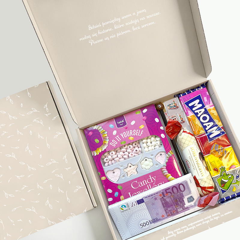 Wnętrze eleganckiego pudełka z różnorodnymi słodyczami, w tym cukierkami, żelkami, oraz gotowym zestawem do samodzielnego ozdabiania.