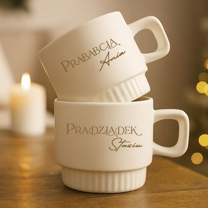 Dwie białe filiżanki z napisami "Prababcia Ania" i "Pradziadek Stasiu", ustawione jedna na drugiej.