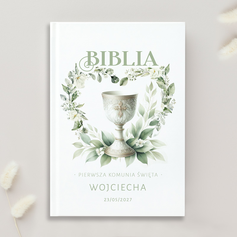 Biblia z okładką ozdobioną gałązkami i kielichem, z napisem "Pierwsza Komunia Święta" i datą