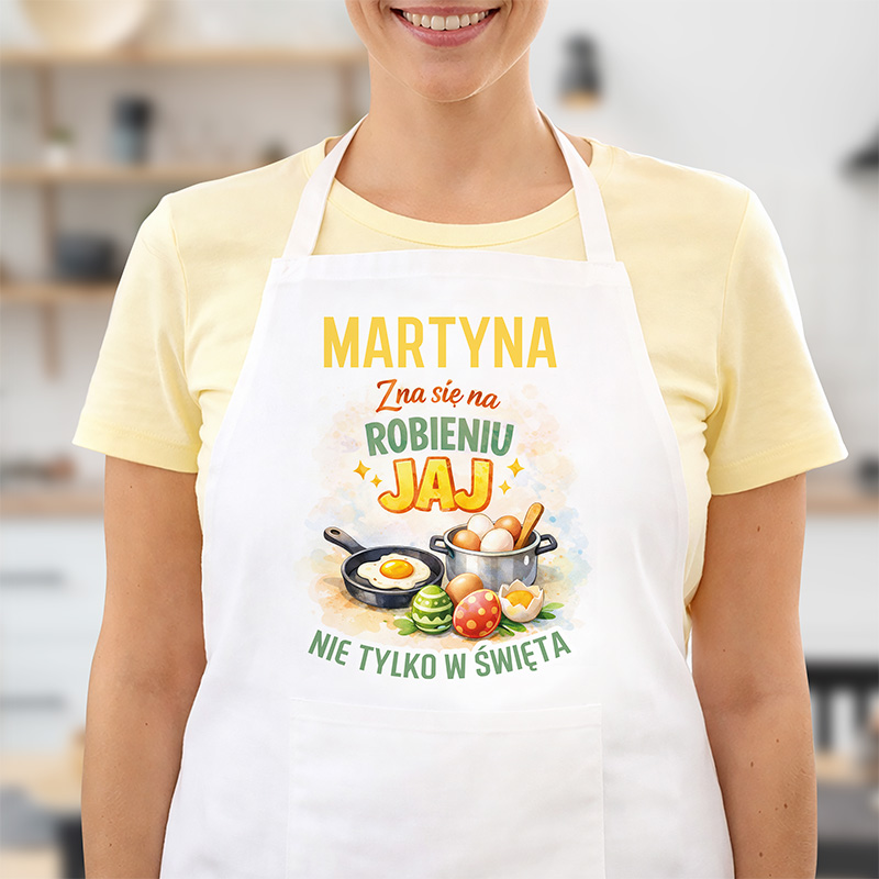 Fartuch z napisem "IMIĘ zna się na robieniu jaj" oraz ilustracjami jajek i garnków.