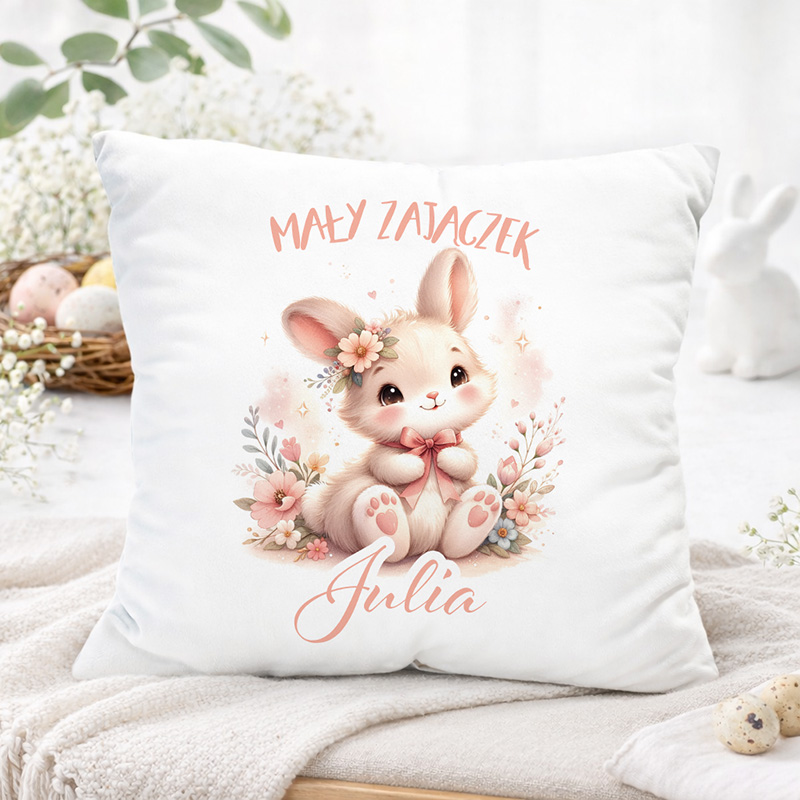 Poduszka z kreskówkowym zajączkiem trzymającym wstążkę, zdobiona kwiatami, z napisem "Mały Zajączek Julia".