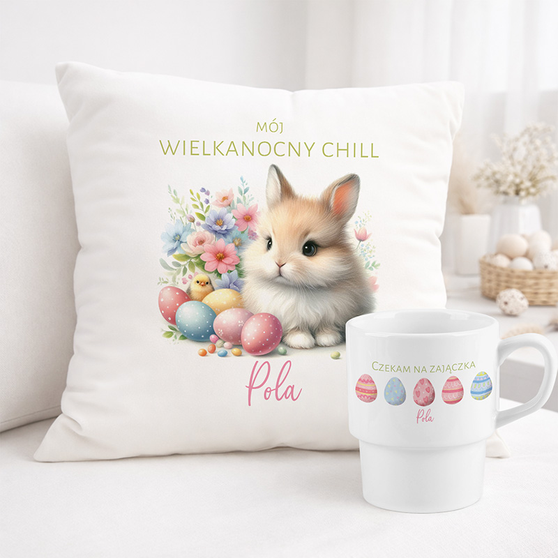 Poduszka z rysunkiem kota na tle kwiatów i pisanek oraz kubek z napisem „Czekam na zajączka”.