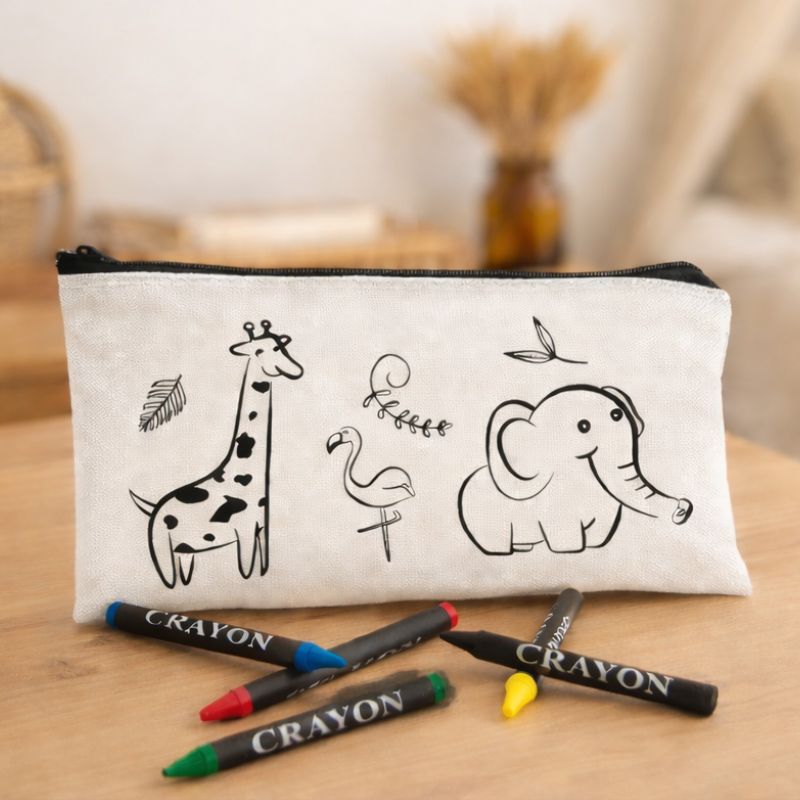Kosmetyczka z rysunkami zwierząt: żyrafy, flaminga i słonia, obok kolorowe kredki.
