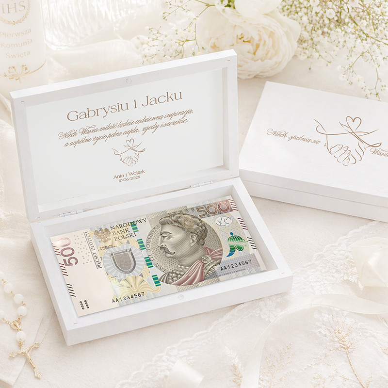 Biała skrzyneczka z otwartą pokrywą, zawierająca banknot 500 złotych, z napisem w środku.