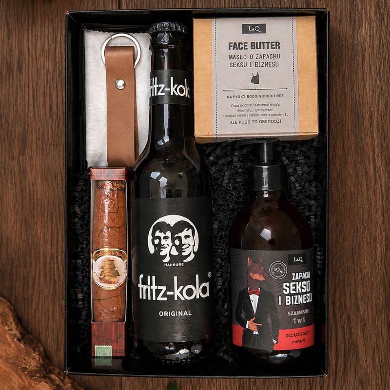 Zestaw prezentowy zawierający butelkę fritz-kola, maść do twarzy, zapach oraz mały przedmiot w opakowaniu.