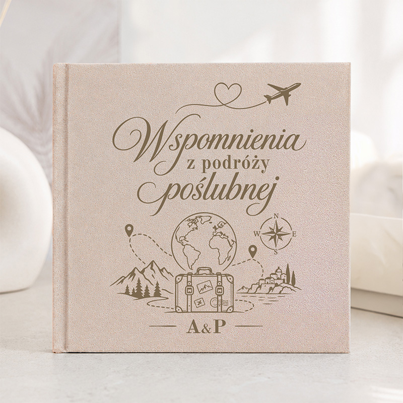 Księga do zapisywania wspomnień z podróży poślubnej, z grafiką przedstawiającą walizkę, góry i inne symbole podróży.