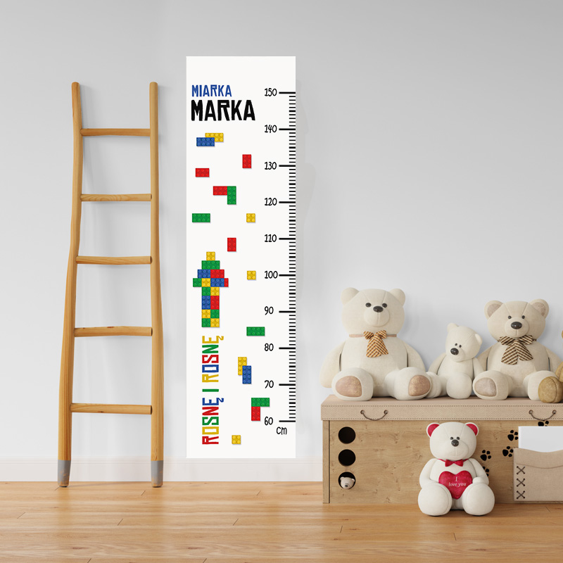 Miarka do mierzenia wzrostu z kolorowymi blokami i nazwą "Miarka" na białym tle, obok drewnianej drabiny i pluszowych misiów.