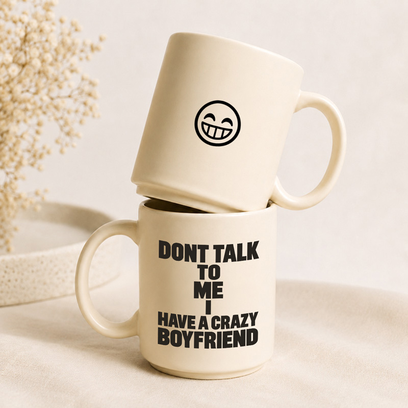 Dwa kubki w jasnym kolorze, jeden z uśmiechniętą buźką na górze i napisami "DON'T TALK TO ME I HAVE A CRAZY BOYFRIEND" na dolnym.