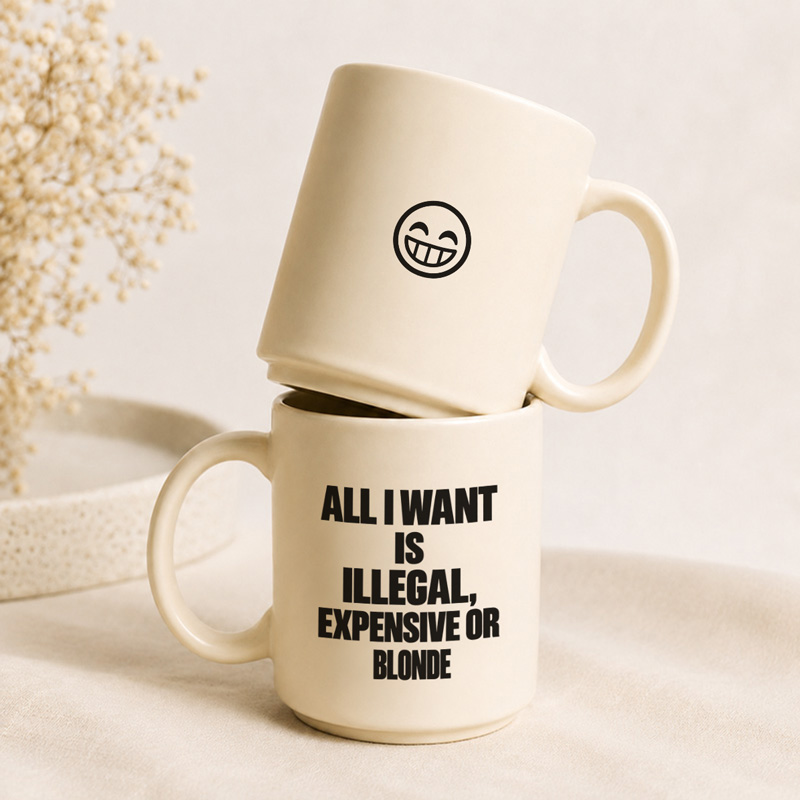 Dwa kubki, jeden z uśmiechniętą buźką, a drugi z napisem „ALL I WANT IS ILLEGAL, EXPENSIVE OR BLONDE”.