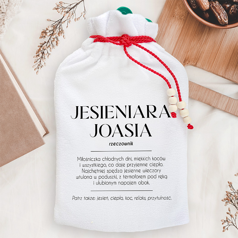 Personalizowany termofor dla jesieniary ma biały miękki pokrowiec z imieniem Joasia i zabawną definicją miłośniczki jesieni.